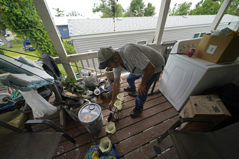 Lester Naquin clears room to sit on the porch of his home that was heavily damaged by Hurricane Ida nine months before, along Bayou Pointe-au-Chien, La., Tuesday, May 24, 2022. (AP Photo/Gerald Herbert)