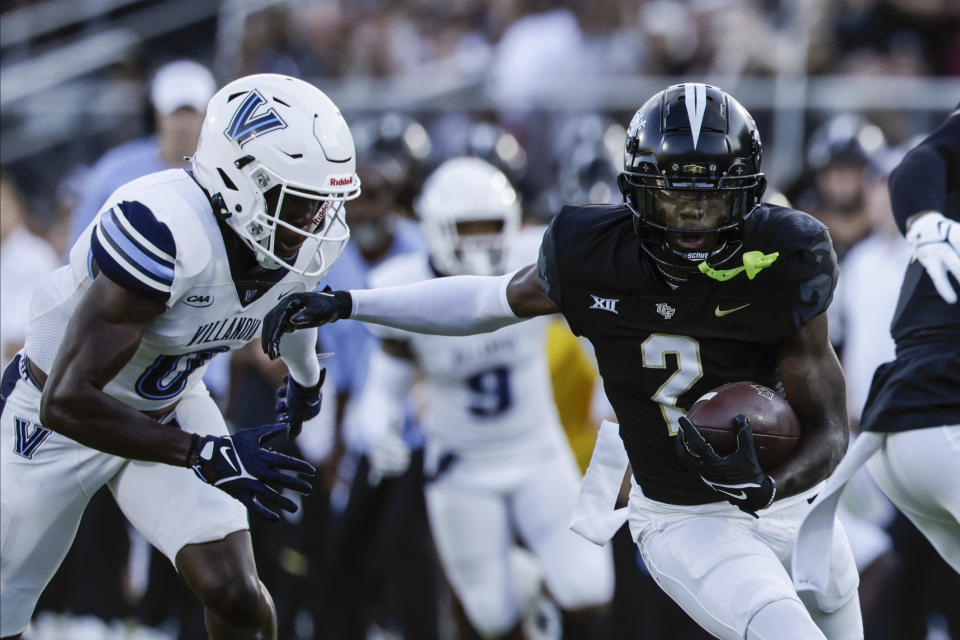 UCF Knights wide receiver Kobe Hudson (2) runs around Villanova Wildcats defensive back Isas Waxter (0) during the first half of an NCAA college football game, Saturday, Sept. 16, 2023, in Orlando, Fla. (AP Photo/Kevin Kolczynski)