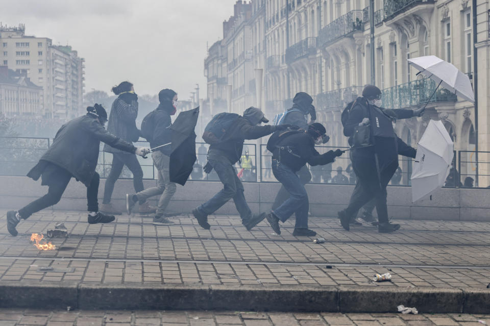 Manifestantes se cubren con sombrillas mientras se enfrentan a policía antidisturbios durante una manifestación en Nantes, Francia, el 23 de marzo de 2023. Los sindicatos franceses organizaron sus primeras manifestaciones masivas el jueves, luego de que el presidente Emmanuel Macron hizo enojar aún más a sus críticos al mantenerse firme con su plan de reformar el sistema de pensiones que su gobierno ha impulsado en el Parlamento sin someterla a una votación. (AP Foto/Jeremías Gonzalez)