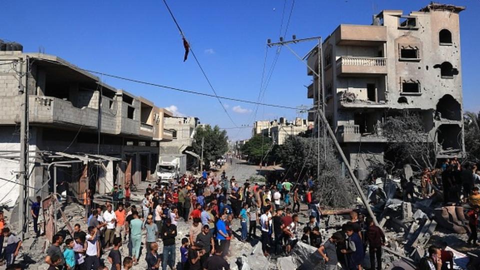 Palestinians gather at the site of a collapsed and damaged buildings following an Israeli airstrike in Rafah, 16 October 2023