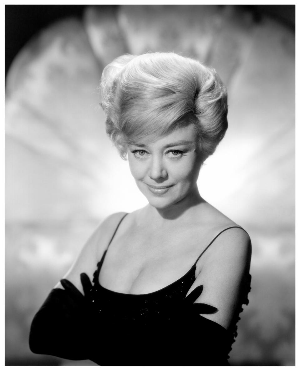 Glynis Johns in a black dress with her arms crossed