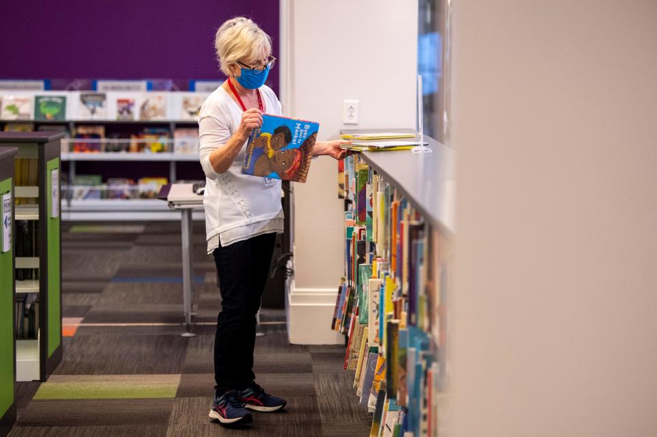 Librarian Page Rita Thompson reshelves books in the children's section of the Nashville Public Library system's Main Library on Thursday, March 25, 2021 in Nashville, Tenn. For the first time since closing their doors last March, three branches of the Nashville Public Library are getting ready to reopen with having re-set the space for social distancing, limited capacity and other COVID-19 protocols.