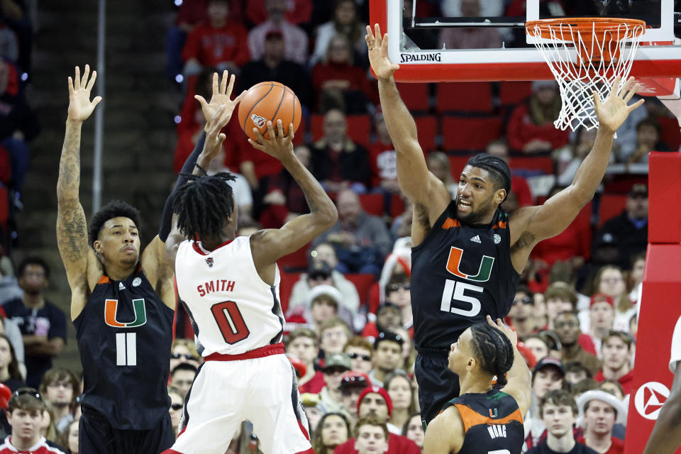 North Carolina State's Terquavion Smith (0) takes a shot between Miami's Jordan Miller (11) and Norchad Omier (15) during the second half of an NCAA college basketball game in Raleigh, N.C., Saturday, Jan. 14, 2023. (AP Photo/Karl B DeBlaker)