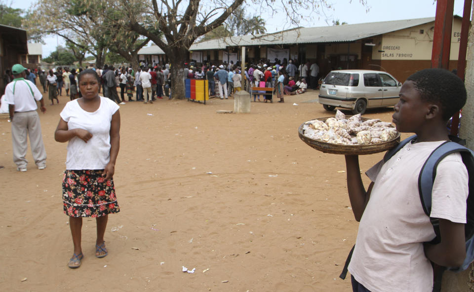 A young boy sells peanuts as voters queue to cast their votes in Maputo, Mozambique, Tuesday, Oct. 15, 2019 in the country's presidential, parliamentary and provincial elections. Polling stations opened across the country with 13 million voters registered to cast ballots in elections seen as key to consolidating peace in the southern African nation. (AP Photo/Ferhat Momade)