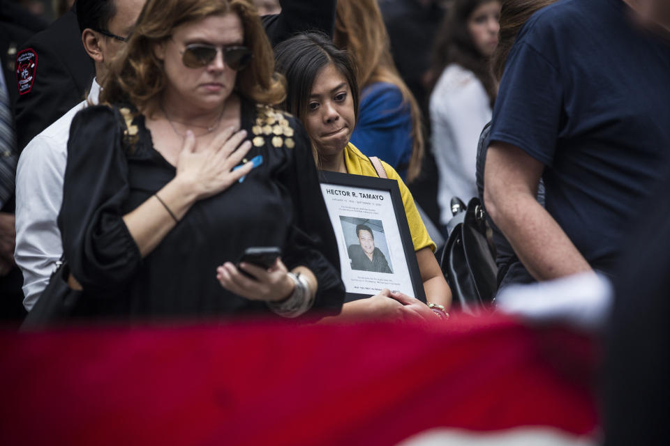 NEW YORK, NY - SEPTEMBER 11: Memorial visitors mourn as officials carry an American flag past them at the beginning of the memorial observances held at the site of the World Trade Center  on September 11, 2014 in New York City. This year marks the 13th anniversary of the September 11th terrorist attacks that killed nearly 3,000 people at the World Trade Center, Pentagon and on Flight 93. (Photo by Andrew Burton/Getty Images)