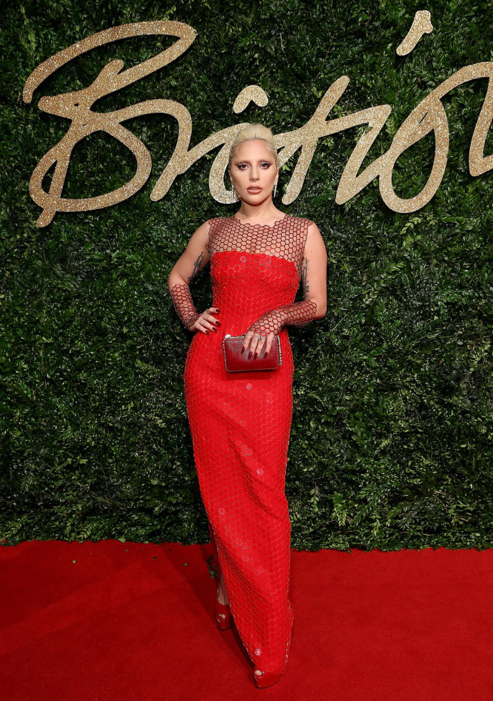 Lady Gaga in a red gown and fingerless gloves with honeycomb detailing by Tom Ford.