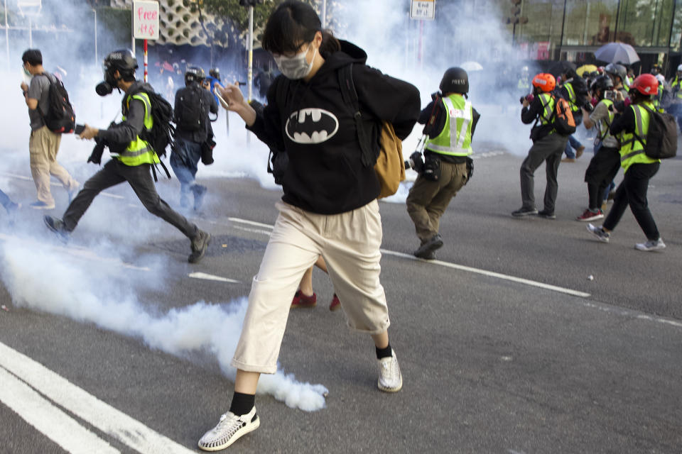 A pro-democracy protester runs away from the tear gas fired by riot police during a rally in Hong Kong, Sunday, Dec. 1, 2019. A huge crowd took to the streets of Hong Kong on Sunday, some driven back by tear gas, to demand more democracy and an investigation into the use of force to crack down on the six-month-long anti-government demonstrations. (AP Photo/Ng Han Guan)