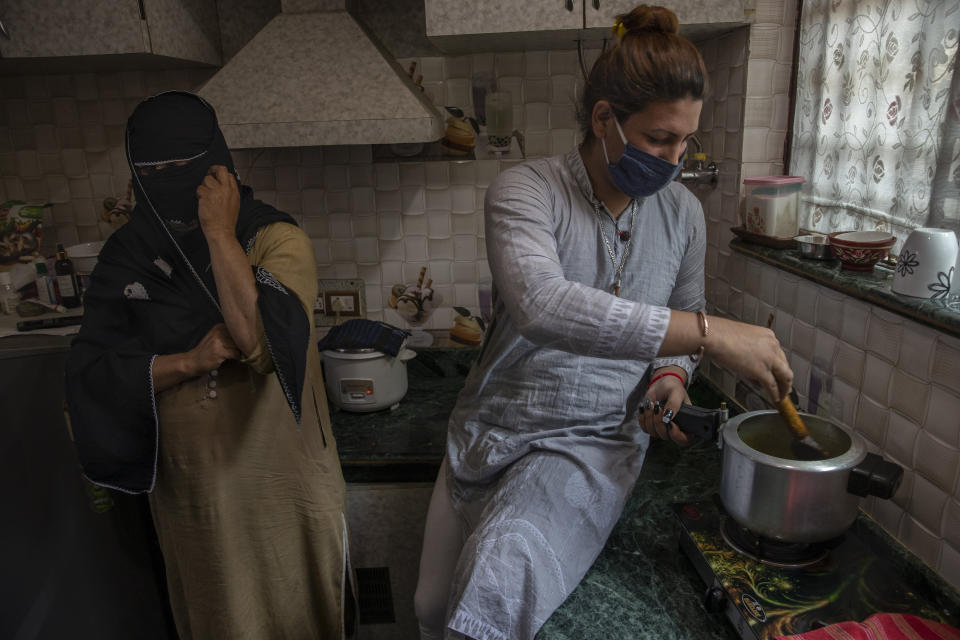 Hinna Bhat, a transgender Kashmiri, cooks as Naina, face covered to hide identity, stands beside during a special meet of their community members in Srinagar, Indian controlled Kashmir, Thursday, June 3, 2021. Life has not been easy for many of Kashmir's transgender people. Most are ostracized by families and bullied in society. They face domestic abuse and end up running away from families at an early age. Some lack housing, education and other basic resources. (AP Photo/ Dar Yasin)