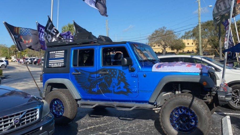 Songs echoing themes of patriotism are played loudly through this Jeep's speakers, as people watch a motorcade of the arriving former President Trump to his criminal documents case hearing in Fort Pierce federal court Feb. 12, 2024