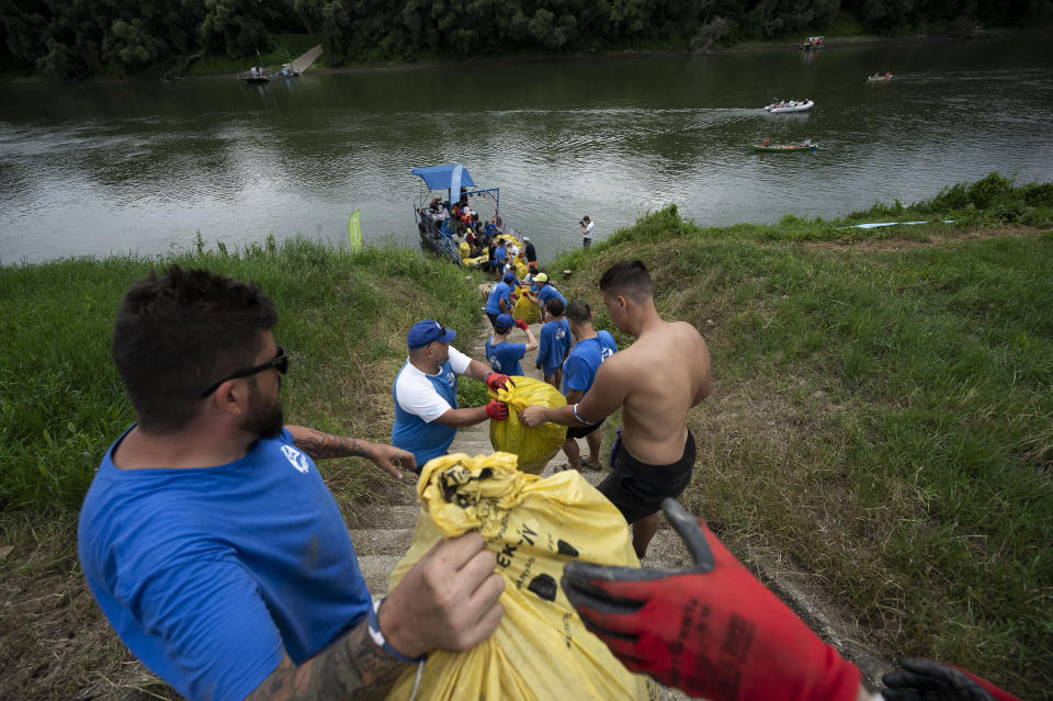 Volunteers stand in a live chain to make it easier to dump the rubbish collected that day on the beach while taking part in the Plastic Cup event near Tiszaroff, Hungary, Tuesday, Aug. 1, 2023. Since its start in 2013, participants in the annual competition — which offers a prize for those who collect the most trash each year — have gathered more than 330 tons (around 727,000 pounds) of waste from the Tisza and other Hungarian waters. (AP Photo/Denes Erdos)