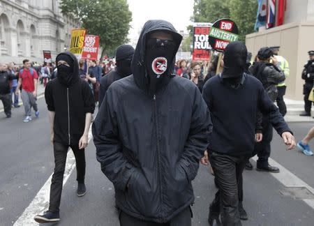 Demonstrators cover their faces as they march during an anti-austerity protest in central London, Britain June 20, 2015. REUTERS/Peter Nicholls