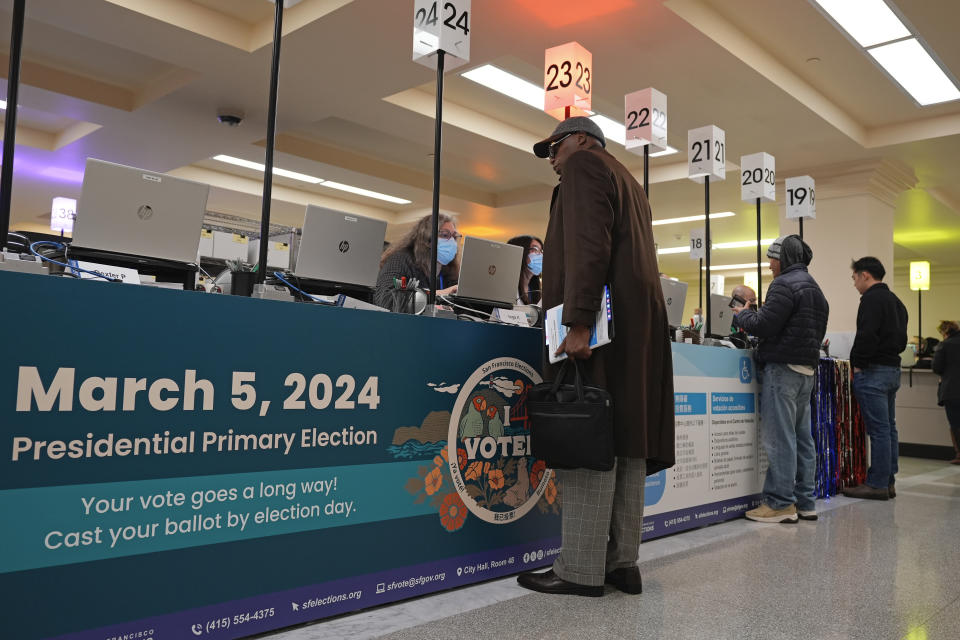 People check in at a counter before voting at City Hall in San Francisco, Tuesday, March 5, 2024. Voters in San Francisco will weigh in on a pair of public safety measures on Tuesday's ballot that reflect frustration over crime and drug use in the politically liberal city, including a proposal to compel treatment for adults using illegal drugs who receive cash welfare benefits. (AP Photo/Eric Risberg)