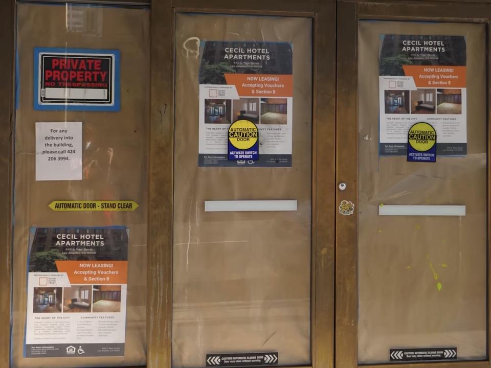 Four glass sliding doors covered with brown paper and signs saying "private property" and posters with apartment rental information.