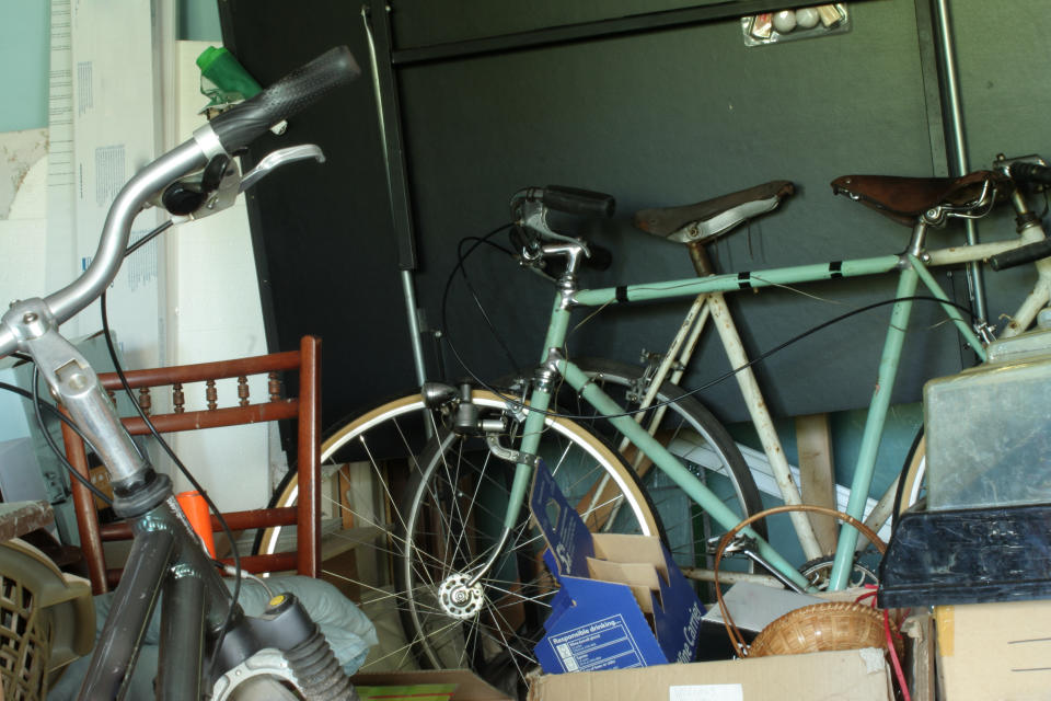 Three bikes surrounded by junk in a garage
