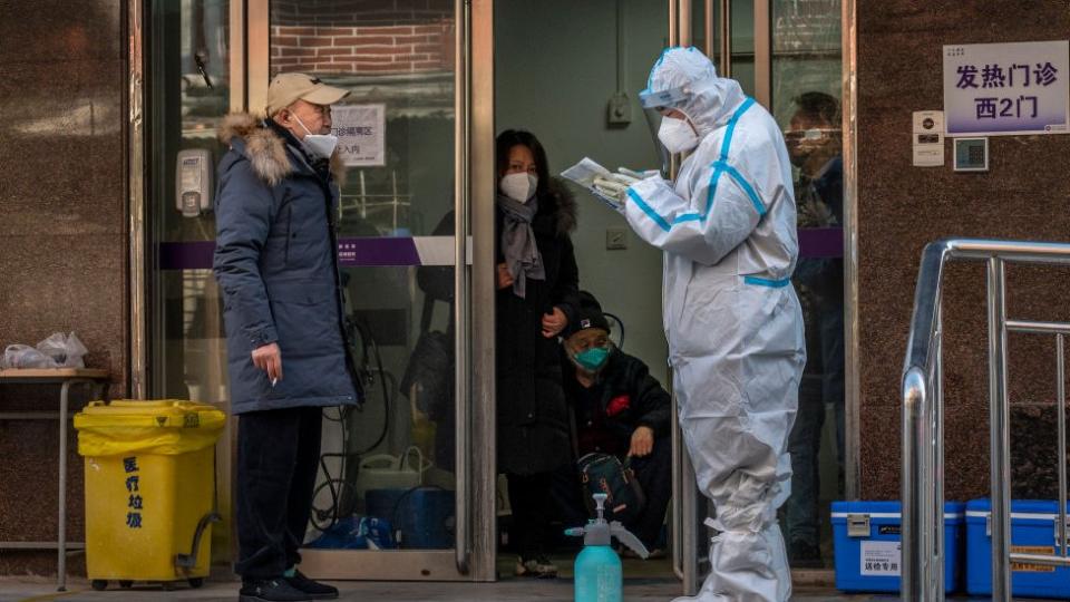 Un trabajador médico usa EPP mientras habla con un paciente en una clínica de covid,