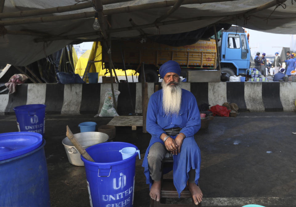 An Indian Farmer sits under a makeshift tent beside a highway, as they continue to block a road leading to Delhi in protest against new farm laws, at Delhi-Uttar Pradesh border, India, Friday, Jan. 22, 2021. Talks between protesting farmers’ leaders and the government ended abruptly in a stalemate on Friday with the agriculture minister saying he has nothing more to offer than suspending contentious agricultural laws for 18 months. The farmers’ organizations in a statement on Thursday said they can’t accept anything except the repeal of the three new laws. (AP Photo/Manish Swarup)