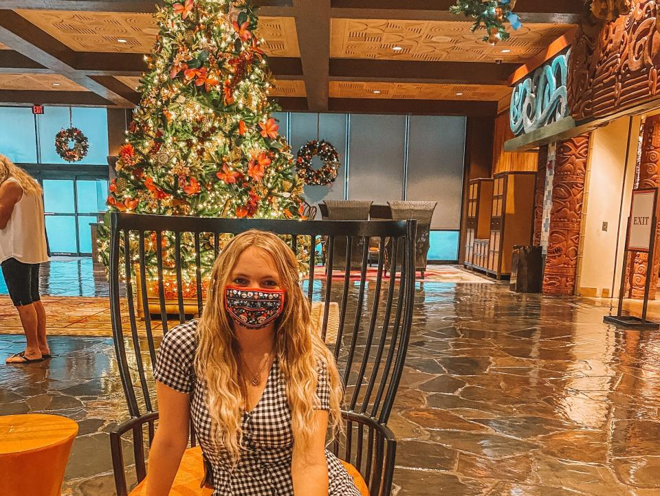 kayleigh sitting in front of a christmas tree at a disney world resort