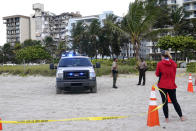 Florida Fish and Wildlife Conservation Commission officials stand outside of a 12-story beachfront condo building which partially collapsed, Friday, June 25, 2021, in the Surfside area of Miami. The apartment building partially collapsed on Thursday. (AP Photo/Lynne Sladky)