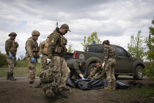 Military medics place bodies of the killed Ukrainian soldiers into plastic bags on the road near Bakhmut, Donetsk region, Ukraine, Thursday, May 11, 2023. (AP Photo/Boghdan Kutiepov)