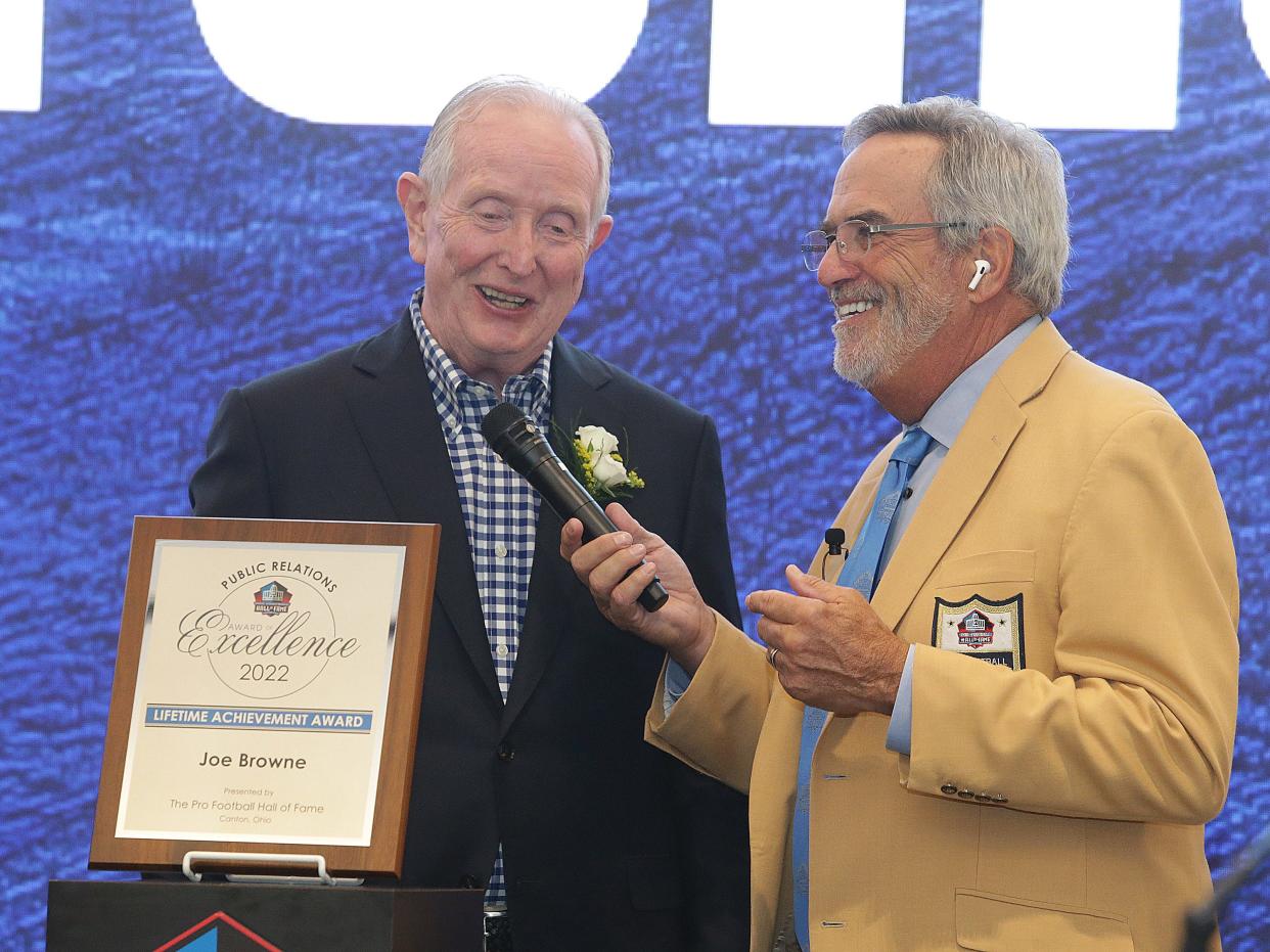 NFL Public Relations associate Joe Browne ,left, is awarded the Pro Football Hall of Fame Award of Excellence from master of ceremonies Hall of Famer Dan Fouts at the Pro Football Hall of Fame Thursday, June 30, 2022. 