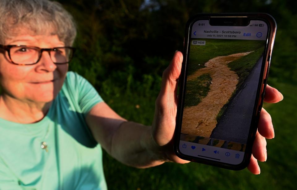 Reba Wittenmeier shows a photograph on her phone of runoff from a debris mountain after a recent rainstorm on Friday, June 23, 2023, in Scottsboro, Tenn. Neighbors are worried the runoff is eroding the roads in the neighborhood, including Old Hydes Ferry Pike.