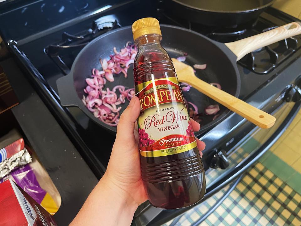 a person holding a bottle of red wine vinegar