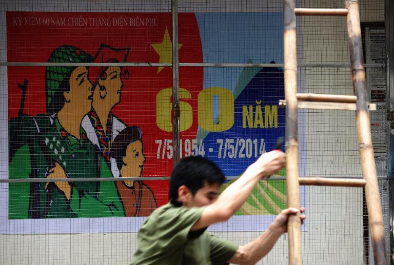 An official installs posters marking the 60th anniversary of the battle of Dien Bien Phu and the 39th anniversary of the fall of Saigon at a local quarter's information billboard in Hanoi on April 22, 2014