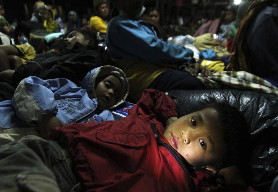 A child refugee lies down at temporary shelter with his family and other villagers. More than 1,500 people have been evacuated from the danger. (Reuters)