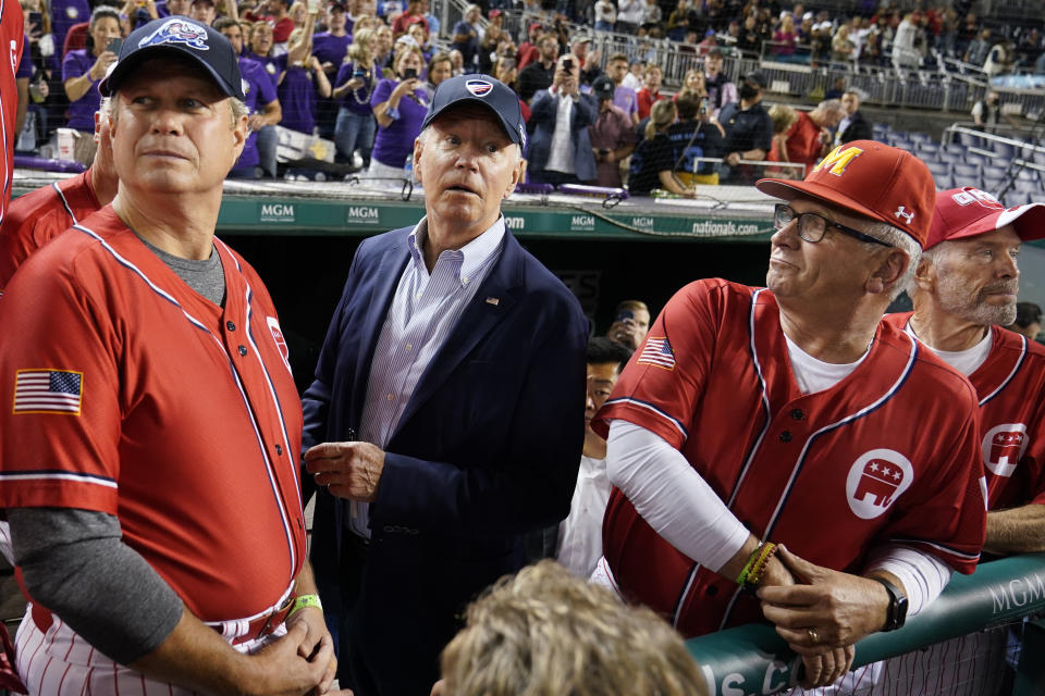 President Joe Biden visits the Republican dugout as he attends the Congressional baseball game at Nationals Park Wednesday, Sept. 29, 2021, in Washington, with Rep. Mike Bost, R-Ill., right, and Rep. Bill Huizenga, R-Mich. The annual baseball game between Congressional Republicans and Democrats raises money for charity. (AP Photo/Susan Walsh)