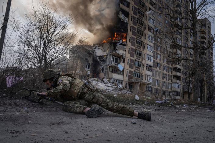 A Ukrainian police officer takes cover in front of a burning building