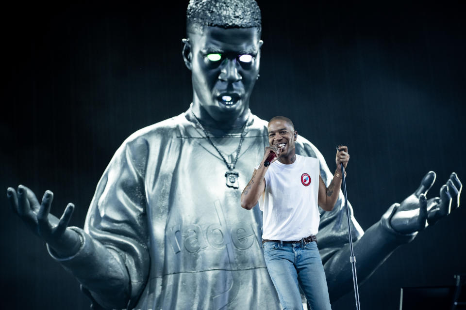 Kid Cudi onstage with a projection of an illustration of him in the background