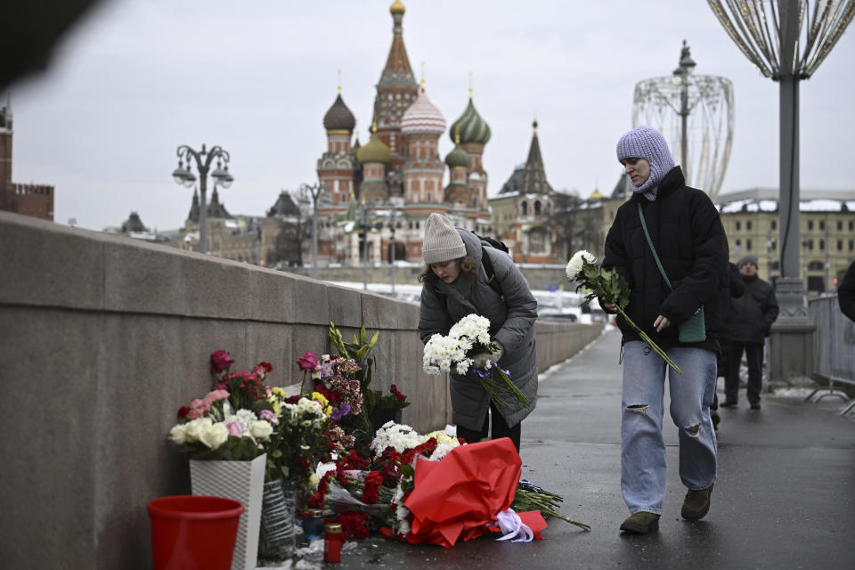 People lay flowers at the place where Russian opposition leader Boris Nemtsov was gunned in 2015, as they come to mark the 9th anniversary of his killing in Moscow, with the Kremlin in the background, Russia, Tuesday, Feb. 27, 2024. (AP Photo)