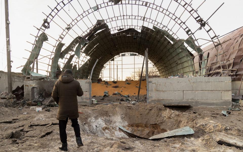 Locals look at a damaged hangar used to store grain after a night rocket attack in Pisochyn, near Kharkiv, northeastern Ukraine