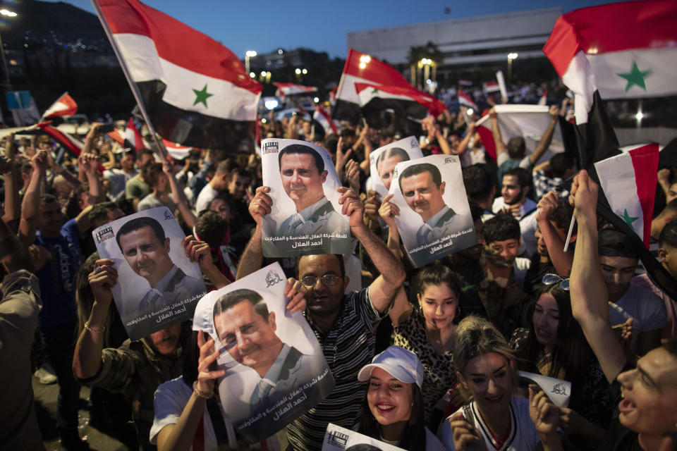 Syrian President Bashar Assad supporters hold up national flags and pictures of Assad as they celebrate at Omayyad Square, in Damascus, Syria, Thursday, May 27, 2021. (AP Photo/Hassan Ammar)