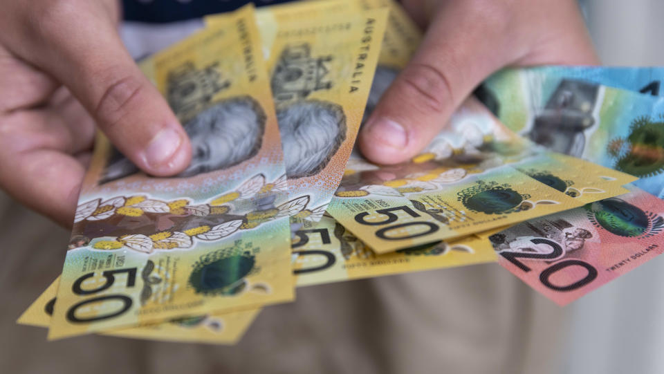 Male person holding some Australian currency. This visual concept evokes ideas around saving money, paying for expenses and investments.