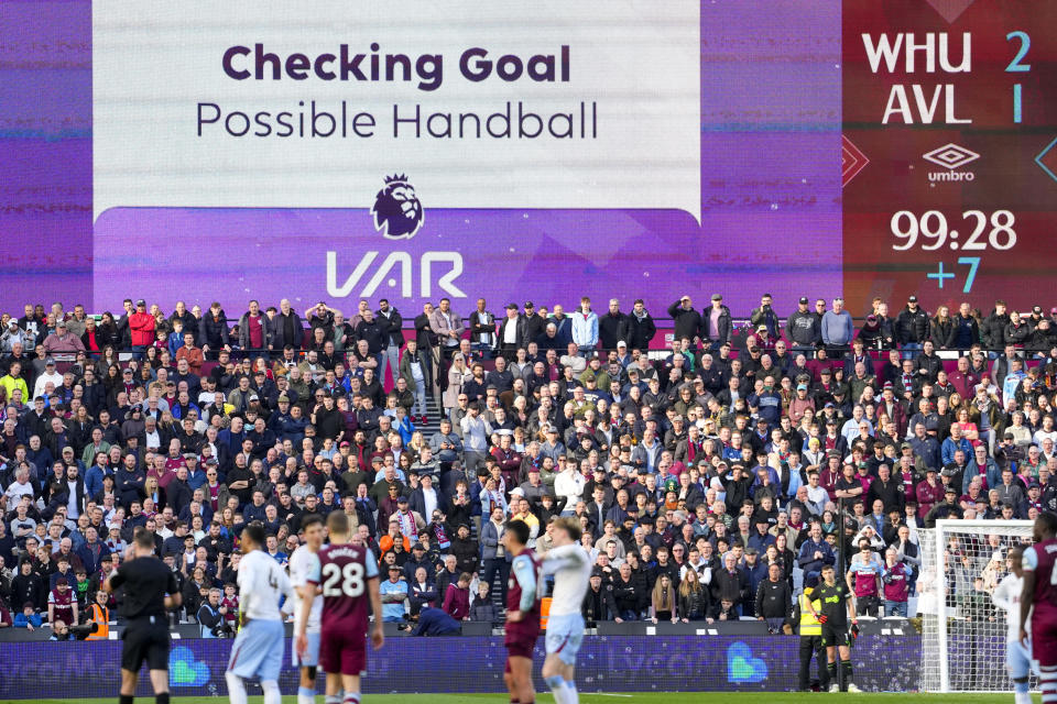 The big screen displays Checking Goal during a VAR review after West Ham's Konstantinos Mavropanos scores a disallowed goal during the English Premier League soccer match between West Ham and Aston Villa, at the London stadium in London, Sunday, March 17, 2024. (AP Photo/Kirsty Wigglesworth)