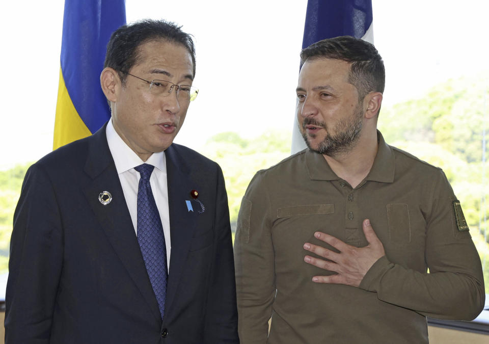 Ukrainian President Volodymyr Zelenskyy, right, chats with Japan's Prime Minister Fumio Kishida, during a group photo session, ahead of a working session on Ukraine at the G7 Summit in Hiroshima, western Japan, Sunday, May 21, 2023. (Kyodo News via AP)