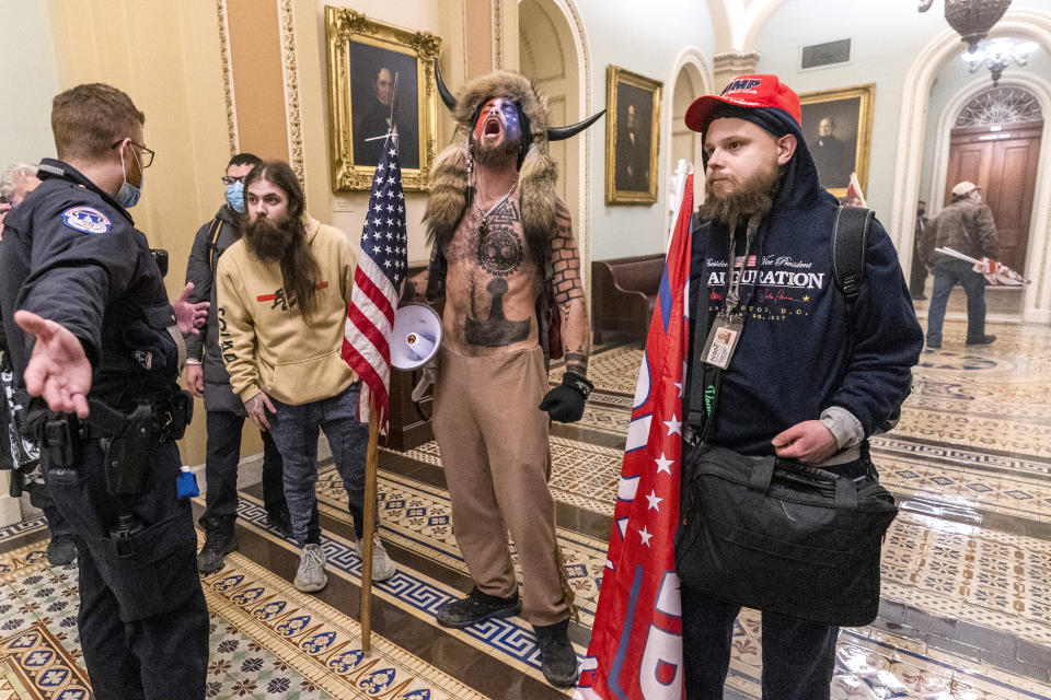 FILE - In this Wednesday, Jan. 6, 2021 file photo, supporters of President Donald Trump, including Jacob Chansley, center with fur and horned hat, are confronted by Capitol Police officers outside the Senate Chamber inside the Capitol in Washington. A video showed Chansley leading others in a prayer inside the Senate chamber. (AP Photo/Manuel Balce Ceneta)
