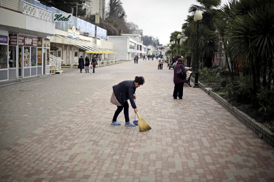 A woman sweeps the boardwalk in front of souvenir shops along the Black Sea, Wednesday, Jan. 29, 2014, in Sochi, Russia, home of the upcoming 2014 Winter Olympics. (AP Photo/David Goldman)