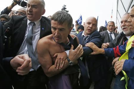 A shirtless Xavier Broseta, Executive Vice President for Human Resources and Labour Relations at Air France, is evacuated by security after employees interrupted a meeting with staff representativesat the Air France headquarters building at the Charles de Gaulle International Airport in Roissy, near Paris, France, October 5, 2015. REUTERS/Jacky Naegelen