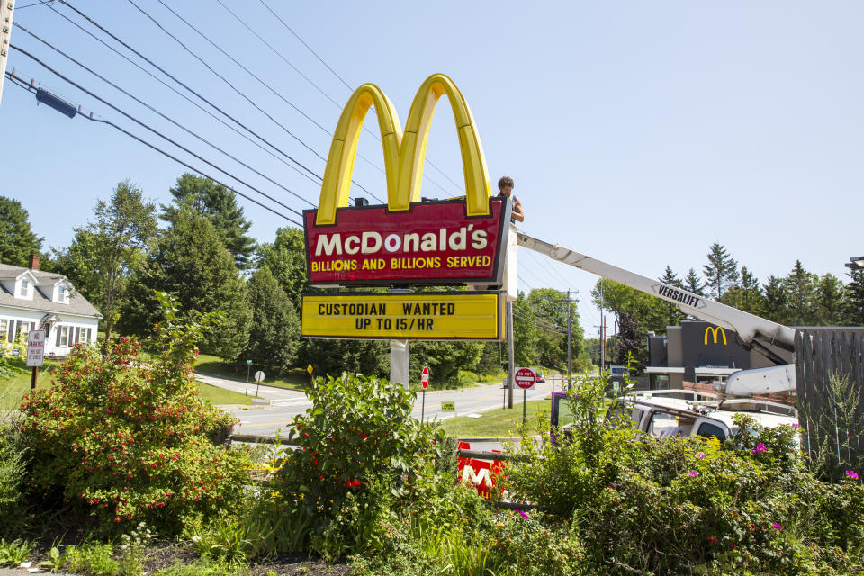 A man works on a McDonald's restaurant sign with a job listing for a custodian paying up to $15 an hour in Bucksport, Maine, on Monday, August 16, 2021. (AP Photo/Ted Shaffrey)