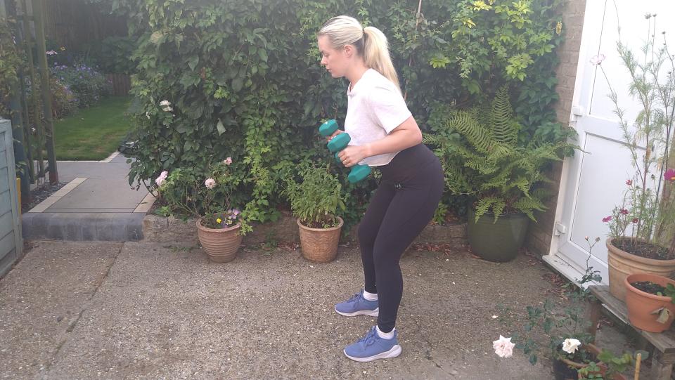 Stacey Carter performs dumbbell row in garden