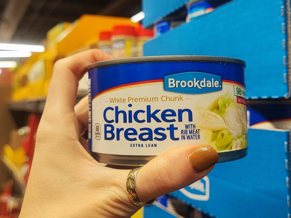 A hand holding a can of Brookdale chicken breast.