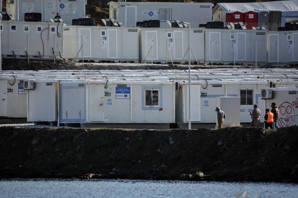 Migrants walk next to container houses at Karatepe refugee camp, on the northeastern Aegean island of Lesbos, Greece, Thursday, Nov. 25, 2021. Pope Francis is heading back to the Greek island of Lesbos to meet migrants and asylum seekers for the second time in five years. (AP Photo/Panagiotis Balaskas)