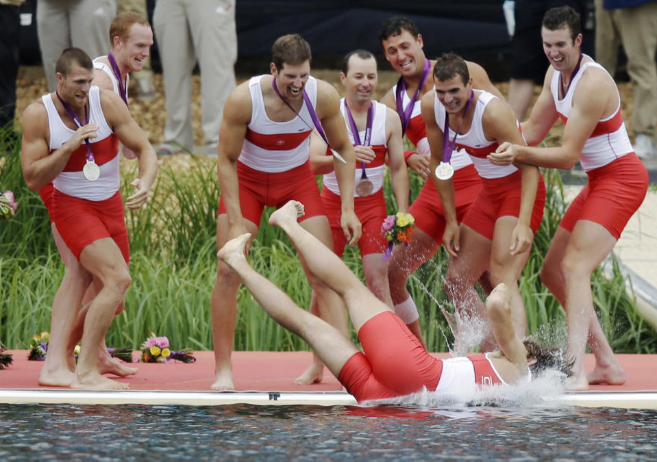 Members of Canada's men's rowing eight throw a teammate in Lake Dorney after winning the silver medal in Eton Dorney, near Windsor, England, at the 2012 Summer Olympics, Wednesday, Aug. 1, 2012. (AP Photo/Natacha Pisarenko)