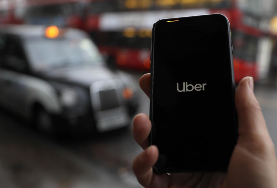 In this posed picture, the Uber app is opened on a mobile phone, backdropped by other transport services in London, Monday, Nov. 25, 2019.  London’s transit authority on Monday refused to renew Uber’s license to operate, with the ride-hailing company vowing to appeal the decision. (AP Photo/Kirsty Wigglesworth)