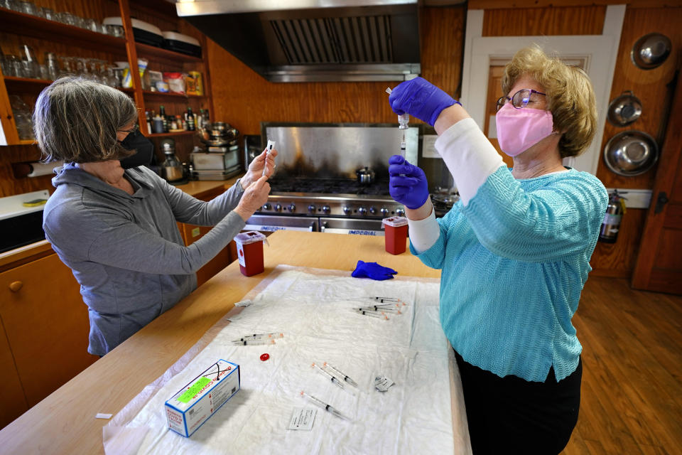 Nurses Sharon Daley, left, and Maureen Giffen fill syringes with the Moderna COVID-19 vaccine in a makeshift clinic in the kitchen of a community center, Friday, March 19, 2021, on Great Cranberry Island, Maine. (AP Photo/Robert F. Bukaty)