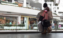 FILE - In this Dec. 22, 2017, file photo a woman shops at the Pentagon City Mall in Arlington, Va. Clothing retailers, particularly those in malls, have been devastated by changing consumer behavior. More than 9,000 stores were shuttered last year. (AP Photo/Susan Walsh, File)