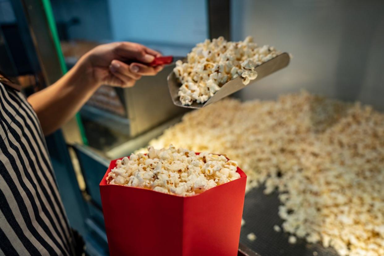 Close-up on a woman serving popcorn at a concession stand at the cinema