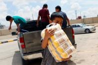 Displaced Libyan people receive aid and supplies outside a hotel used as a shelter, in Tajura neighborhood, east of Tripoli